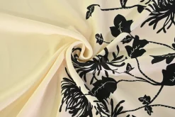 Viscose stretch crêpe – Zwarte bloem op champagne randdesign